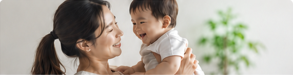 幼い子どもを抱き、笑顔を交わす母親